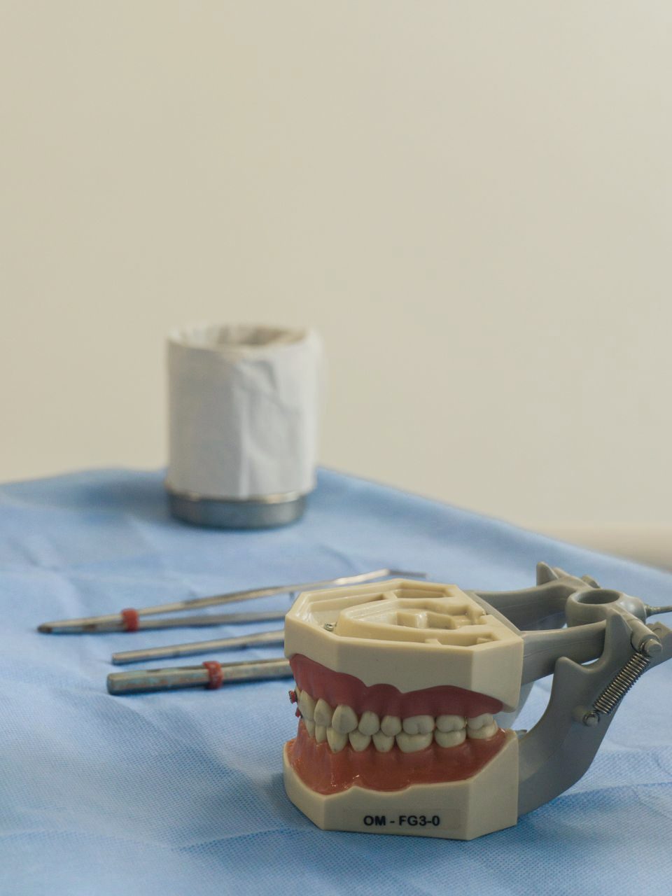 An implant-supported denture model resting beside lab tools